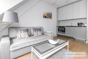 встроенная маленькая кухня с белым верхом, серым низом и деревянным полом